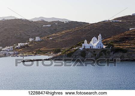 Stock Photograph - Port and white church on a cliff at the water's edge; Ios, Greece. Fotosearch