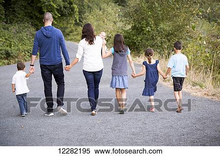 Stock Photography - Portrait of a family with five children walking hand in hand down a path; Chilliwack, British Columbia, Canada. Fotosearch