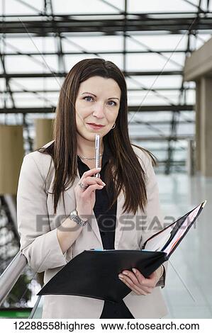 Portrait of a mature business woman holding a portfolio in the atrium of an office building; Edmonton, Alberta, Canada View Large Photo Image Stock Photograph - Portrait of a mature business woman holding a portfolio in the atrium of an office building; Edmonton, Alberta, Canada. Fotosearch