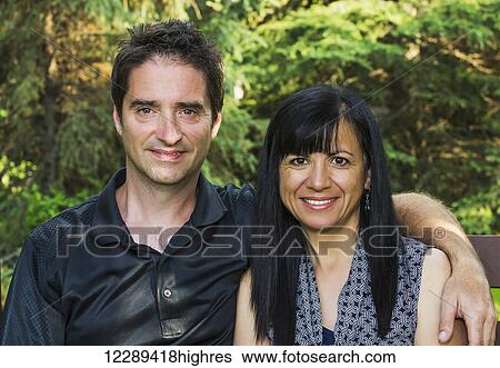 Stock Photograph - Portrait of a mature couple outdoors on a bench in autumn; Sherwood Park, Alberta, Canada. Fotosearch
