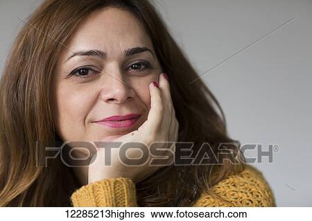 Stock Photograph - Portrait of a Nicaraguan woman smiling and leaning on her hand; Toronto, Ontario, Canada. Fotosearch
