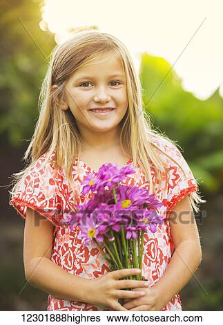 Stock Photograph - Portrait of a smiling cute little girl with flowers. Fotosearch