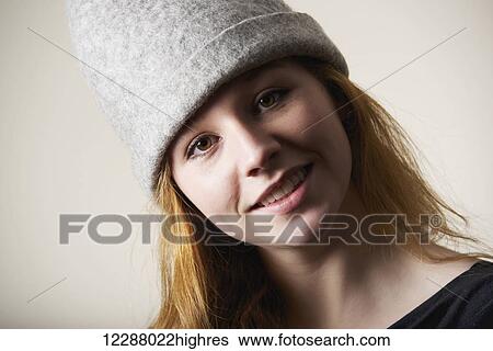 Stock Photograph - Portrait of a smiling young woman with red hair and a grey hat; Caldecott, England. Fotosearch