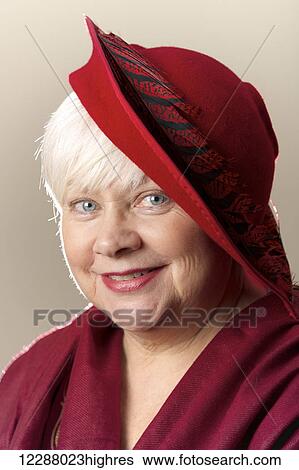 Stock Photograph - Portrait of a white-haired woman in a red hat; Caldecott, England. Fotosearch