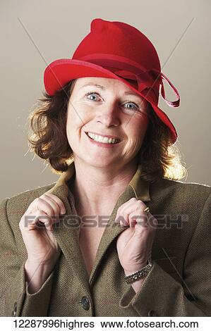 Portrait of a woman with brunette hair wearing a red hat holding jacket lapels; Caldecott, England View Large Photo Image Stock Photograph - Portrait of a woman with brunette hair wearing a red hat holding jacket lapels; Caldecott, England. Fotosearch