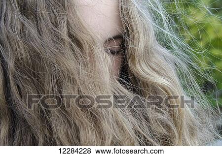 Stock Photo - Portrait of a woman with eyes closed and long blond hair hanging over her face; Lake of the Woods, Ontario, Canada. Fotosearch