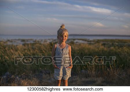 Stock Photograph - Portrait of a young girl on a beach at sunset; Surrey, British Columbia, Canada. Fotosearch