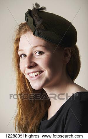 Stock Photograph - Portrait of a young woman with long red hair in a green hat with bow; Caldecott, England. Fotosearch