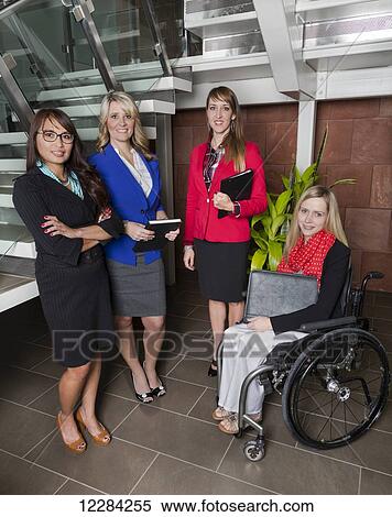Stock Photography - Portrait of four professional business women in the lobby of an office, one of which is a paraplegic in a wheelchair; St. Albert, Alberta, Canada. Fotosearch