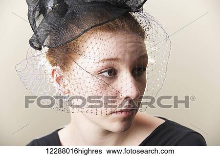 Stock Photograph - Portrait of redhead in veiled black hat; Caldecott, England. Fotosearch