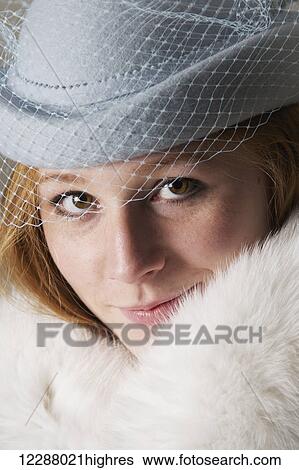 Stock Photograph - Portrait of redhead woman in blue veiled hat and white fur; Caldecott, England. Fotosearch