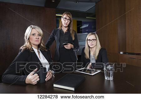 Stock Photo - Portrait of three professional business women during a training session in a boardroom; St. Albert, Alberta, Canada. Fotosearch