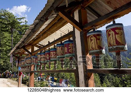 Stock Photograph - Prayer wheels and prayer flags along Taktsang trail; Paro, Bhutan. Fotosearch