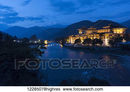 Stock Photograph - Punakha Dzong illuminated at dusk; Punakha, Bhutan. Fotosearch