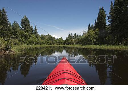 Stock Photography - Red bow of a boat on a tranquil lake; Ontario, Canada. Fotosearch