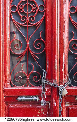 Stock Photograph - Red door with decorative windows chained shut with a padlock; Athens, Greeec. Fotosearch