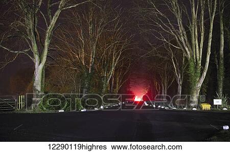 Stock Photograph - Red light, smoke and flames glowing at the end of a driveway; Doxford, England. Fotosearch
