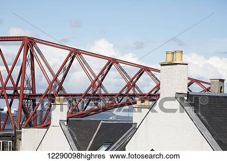 Stock Photograph - Red metal bridge with houses and chimneys in the foreground; Edinburgh, Scotland. Fotosearch