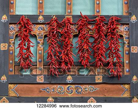 Stock Photograph - Red peppers hanging on an ornate wall; Paro, Bhutan. Fotosearch