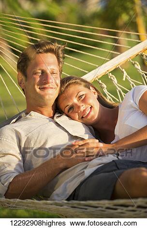 Romantic couple relaxing in tropical hammock at sunset View Large Photo Image Stock Photograph - Romantic couple relaxing in tropical hammock at sunset. Fotosearch