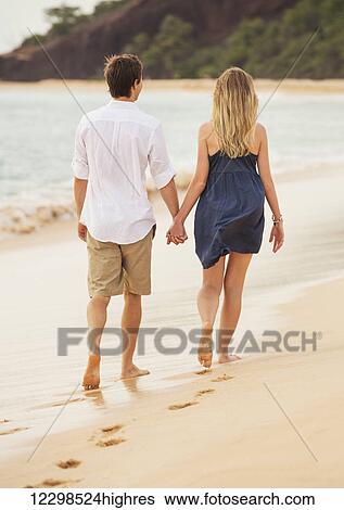 Romantic happy couple walking on beach at sunset. Smiling holding hands. Man and woman in love View Large Photo Image Stock Photograph - Romantic happy couple walking on beach at sunset. Smiling holding hands. Man and woman in love. Fotosearch