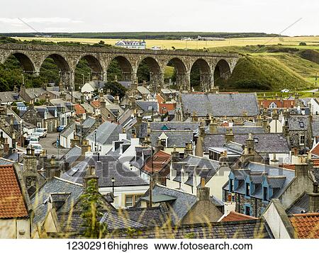 Stock Photograph - Rooftops of houses and an old stone bridge with arches; Cullen, Moray, Scotland. Fotosearch