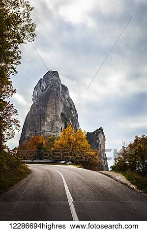 Stock Photograph - Rugged cliffs, road and autumn foliage; Meteora, Greece. Fotosearch