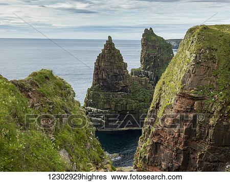 Stock Photograph - Rugged peaked sea stacks along the coast of Duncansby Head; Scotland. Fotosearch