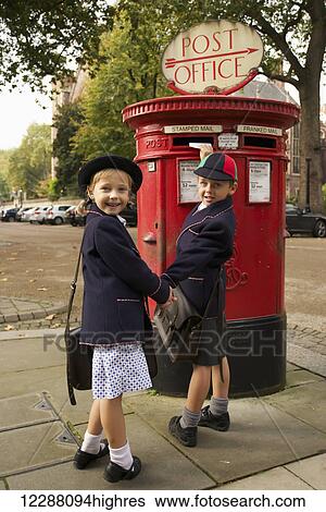 Stock Photograph - Schoolboy and sister smiling while posting letter; London, England. Fotosearch