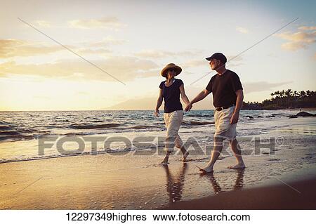 Stock Photograph - Senior Couple Enjoying Sunset at the Beach. Fotosearch