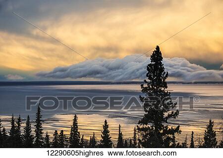 Setting sun sets the clouds aglow over Cook Inlet near Anchorage, Alaska. View Large Photo Image Stock Photograph - Setting sun sets the clouds aglow over Cook Inlet near Anchorage, Alaska.. Fotosearch