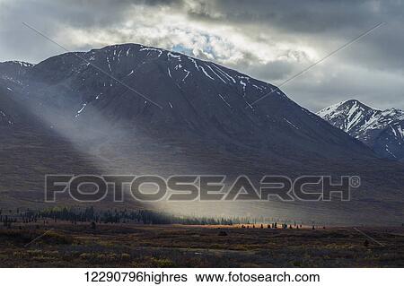 Stock Photograph - Shaft of light lights up colorful tundra along the Haines Highway near Mule Creek, Alsek-Tatshenshini Wilderness, British Columbia, Canada. Fotosearch