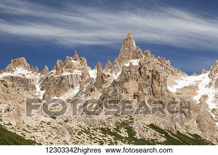 Stock Photograph - Sharp mountain peaks with remaining snow against blue sky with a few wispy clouds; Argentina. Fotosearch