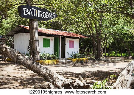Stock Photograph - Sign for the bathrooms outside a small structure with two doorways at Playa Hermosa, near San Juan Del Sur; Nicaragua. Fotosearch