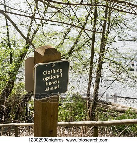 Stock Photograph - Sign on the shore for a beach where clothing is optional; Vancouver, British Columbia, Canada. Fotosearch