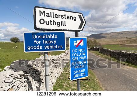 Stock Photograph - Signs on a narrow road warning wagons against following their Sat-Nav systems; Cumbria, England. Fotosearch