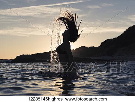 Silhouette of a woman in waist-deep water flipping her wet long hair up in the air; Tarifa, Cadiz, Andalusia, Spain View Large Photo Image Stock Photograph - Silhouette of a woman in waist-deep water flipping her wet long hair up in the air; Tarifa, Cadiz, Andalusia, Spain. Fotosearch