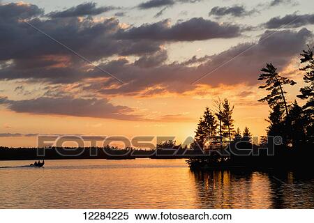 Silhouette of people in a canoe on a tranquil lake at sunset; Ontario, Canada View Large Photo Image Stock Photography - Silhouette of people in a canoe on a tranquil lake at sunset; Ontario, Canada. Fotosearch