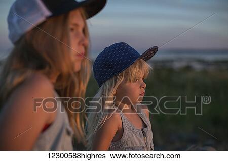 Stock Photograph - Sisters together on the beach at sunset; Surrey, British Columbia, Canada. Fotosearch