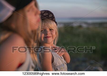 Stock Photograph - Sisters together on the beach at sunset; Surrey, British Columbia, Canada. Fotosearch