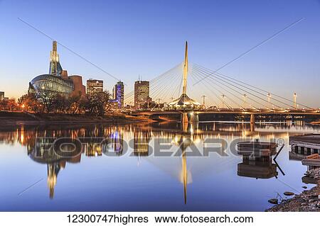 Stock Photograph - Skyline of Winnipeg at night, with Canadian Museum for Human Rights and Esplanade Riel Bridge reflected in the Red River; Winnipeg, Manitoba, Canada. Fotosearch
