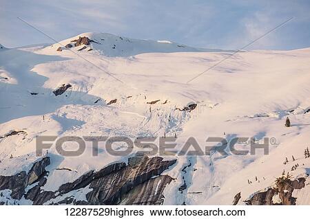 Stock Photograph - Snow covered peaks bathed in sunset light, Kings Bay, Prince William Sound; Whittier, Alaska, United States of America. Fotosearch