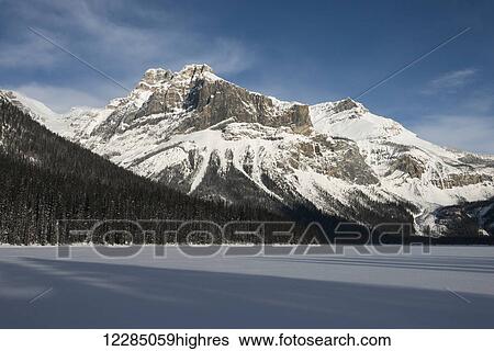 Stock Photograph - Snow on the rugged Canadian Rocky Mountains and a snow covered field, Yoho National Park; Field, British Columbia, Canada. Fotosearch