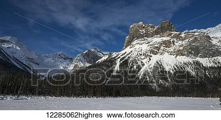 Stock Photograph - Snow on the rugged Canadian Rocky Mountains and a snow covered field, Yoho National Park; Field, British Columbia, Canada. Fotosearch