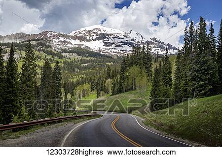 Snowcapped Rocky Mountains in the background with a winding mountain road stretching into the distance; Colorado, United States of America View Large Photo Image Stock Photograph - Snowcapped Rocky Mountains in the background with a winding mountain road stretching into the distance; Colorado, United States of America. Fotosearch