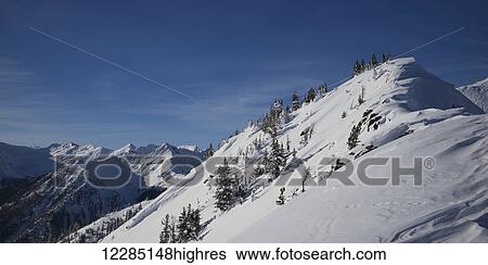 Snowy mountain slope with blue sky and view of mountain range; Kicking Horse, British Columbia, Canada View Large Photo Image Stock Photograph - Snowy mountain slope with blue sky and view of mountain range; Kicking Horse, British Columbia, Canada. Fotosearch