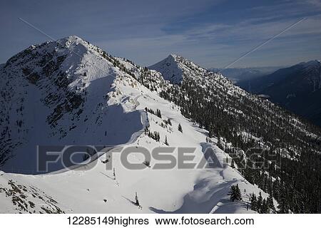 Snowy mountain slope with blue sky and view of mountain range; Kicking Horse, British Columbia, Canada View Large Photo Image Stock Photograph - Snowy mountain slope with blue sky and view of mountain range; Kicking Horse, British Columbia, Canada. Fotosearch