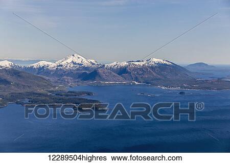 Stock Photograph - Snowy mountains rise above the ocean in Ketchikan, Southeast Alaska, USA, Winter. Fotosearch