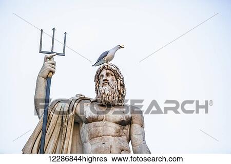 Stock Photograph - Statue of a male figure with beard and pitchfork and a bird perched on it's head, Fountain of Neptune, People's Square; Rome, Italy. Fotosearch
