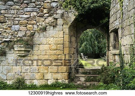 Stock Photograph - Stone wall overgrown with plants and steps up to a walkway. Fotosearch